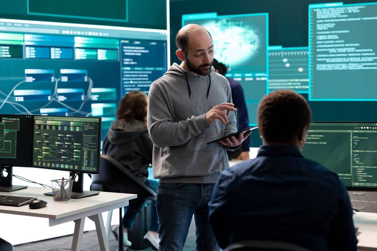 A professor teaching students about cybersecurity and IT in a hands-on IT lab.