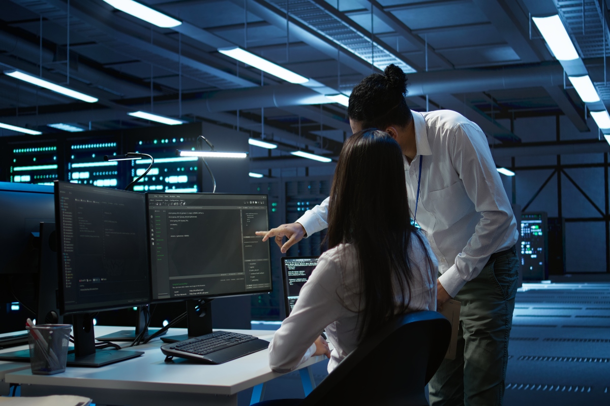 A mentor showing a cybersecurity intern how to do something on the computer.